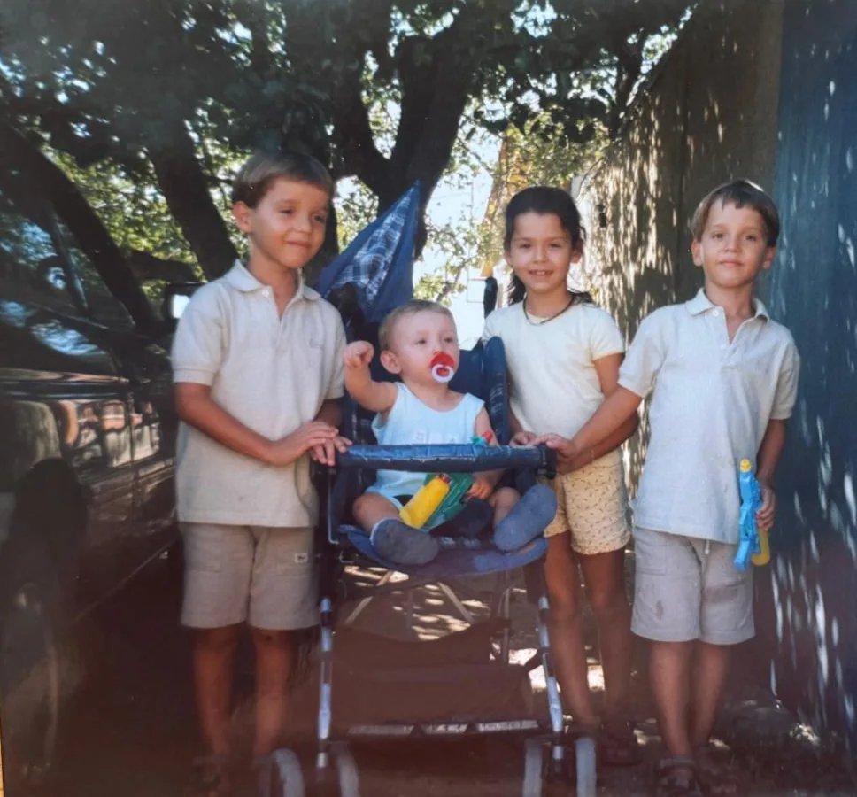 Four children on a tree-lined street, the youngest in a stroller