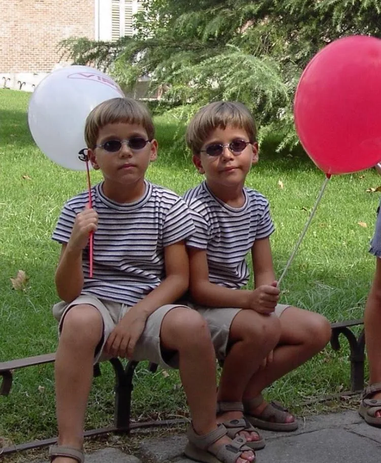 Alejandro and Alberto as small boys in matching striped t-shirts and sunglasses on a bench