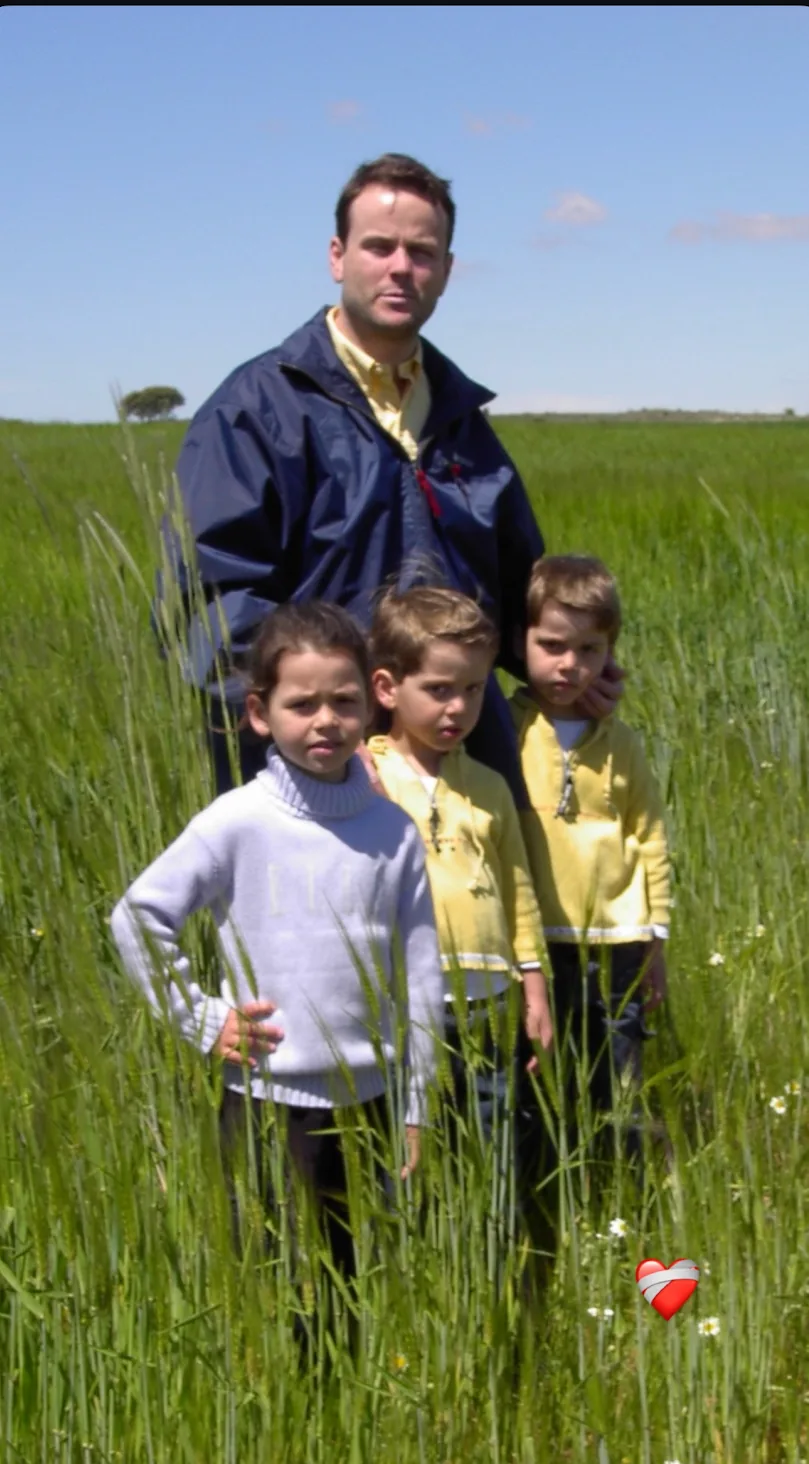 A man with three children in a green field