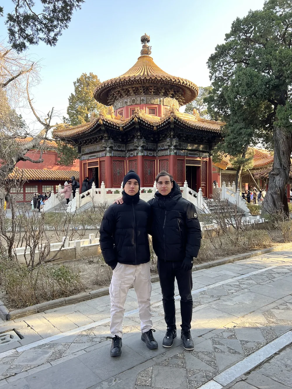 The twins in winter coats in front of a pagoda